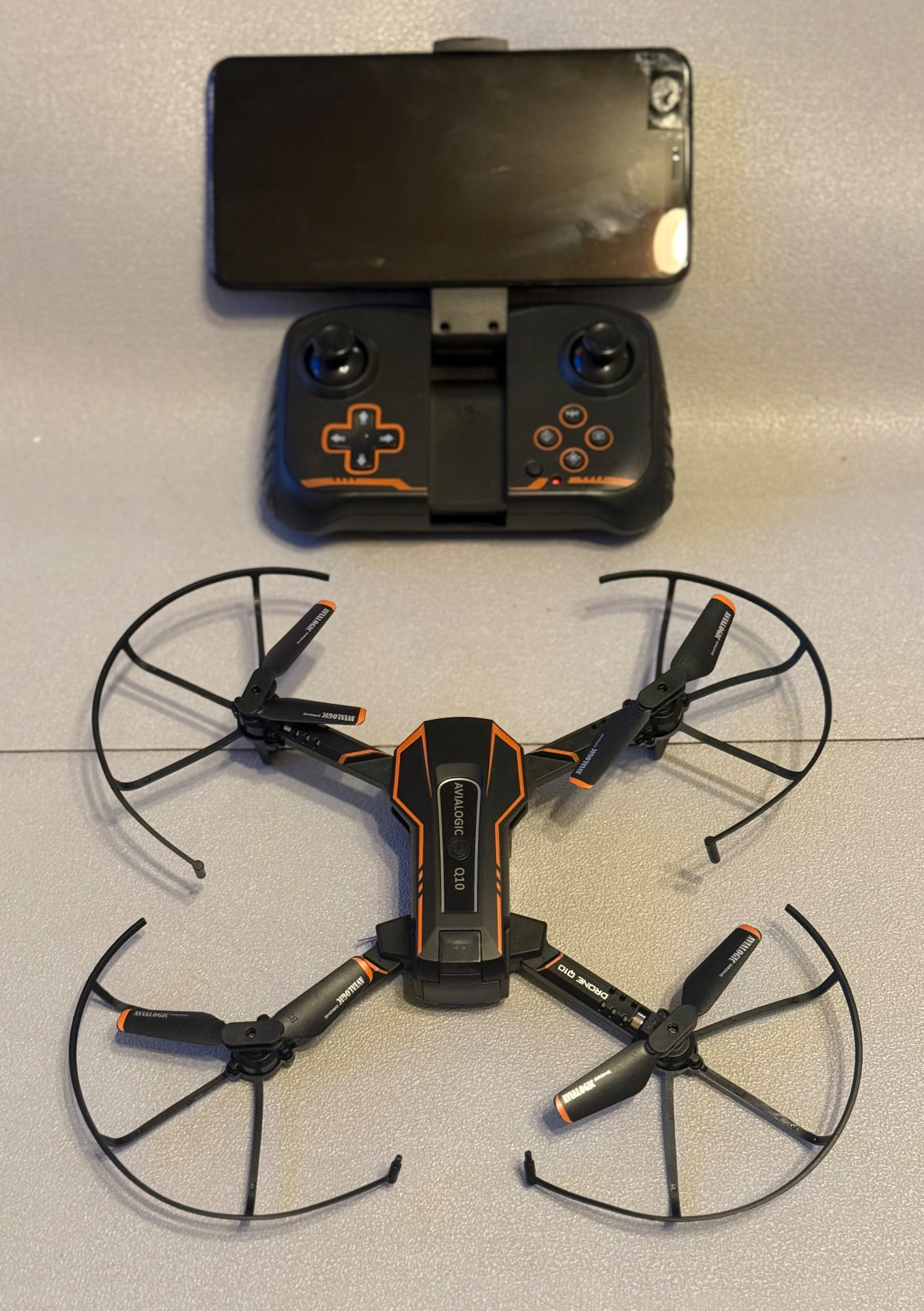 Avialogic Q10 folding camera drone with prop guards next to its phone-mount controller
