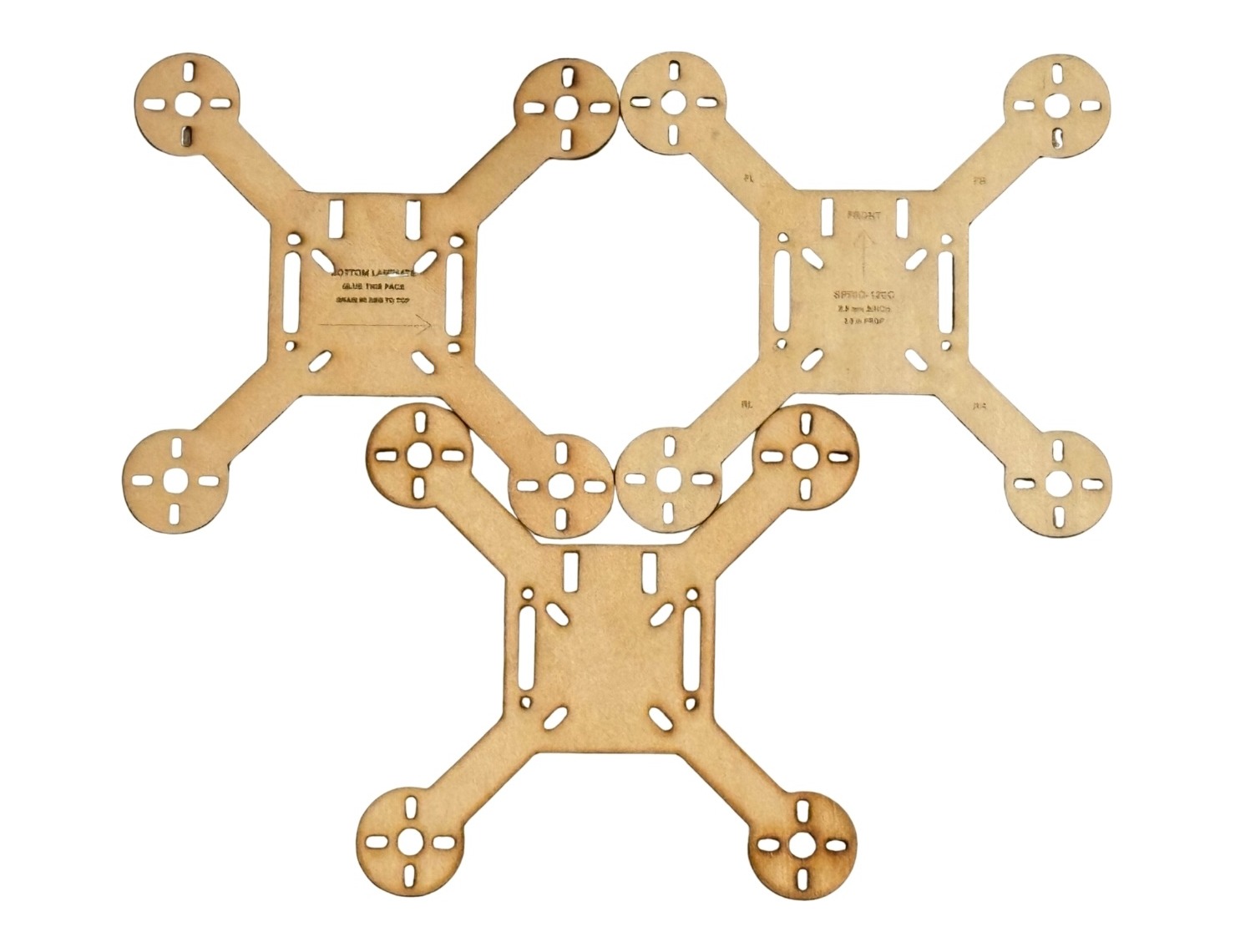 Laser-cut SPRIG-120C quadcopter frame plates laid flat, with a basswood bottom plate