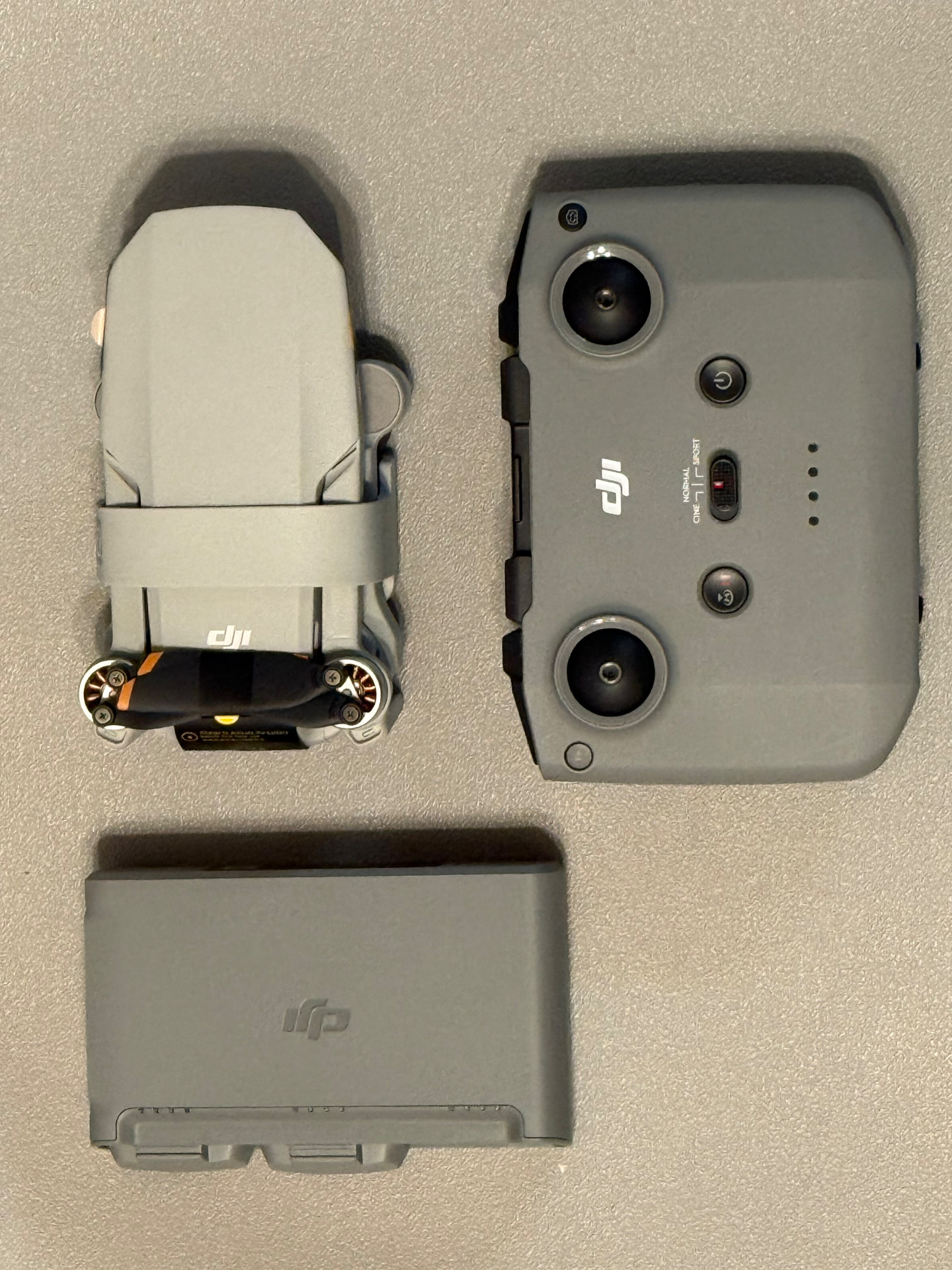 DJI Mini folding camera drone with its controller and a spare intelligent flight battery