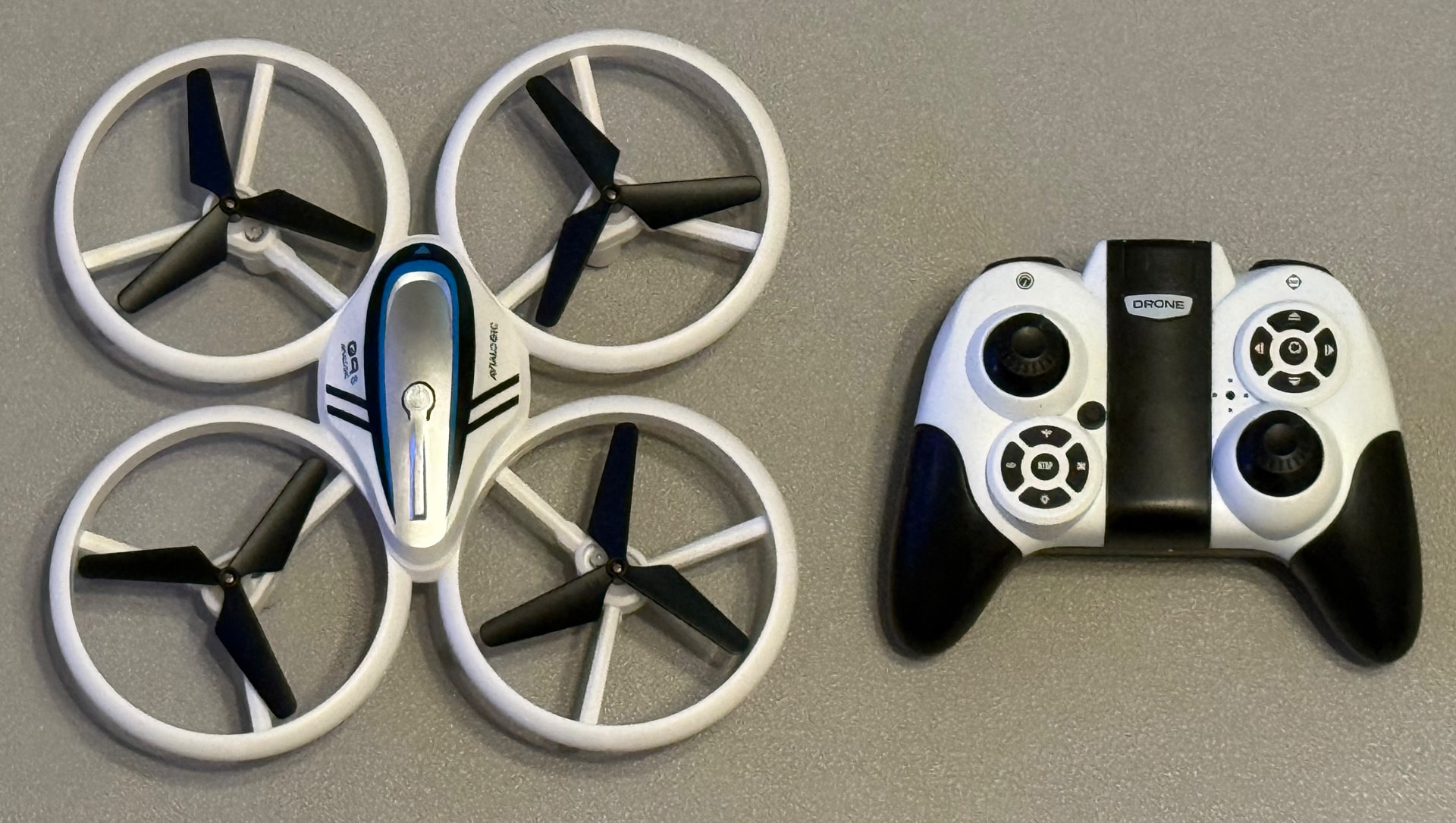 Small white ducted-rotor trainer quadcopter beside its white handheld controller