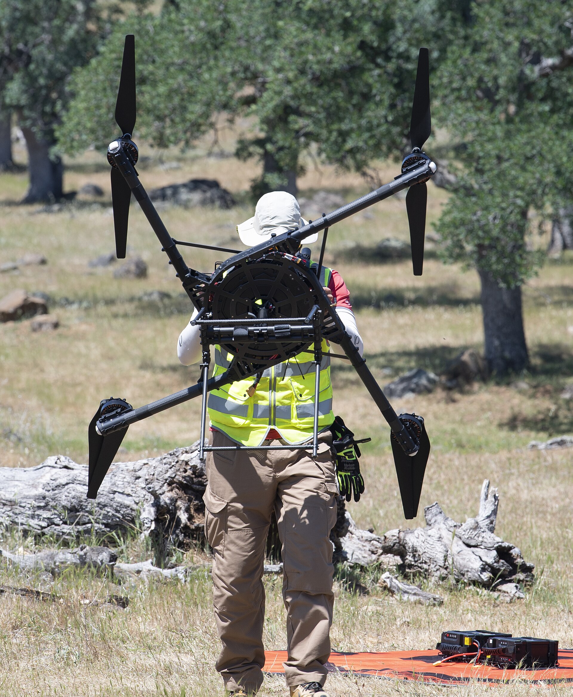 NASA field crew member in a high-visibility vest carrying a large multirotor aircraft during STEReO field testing