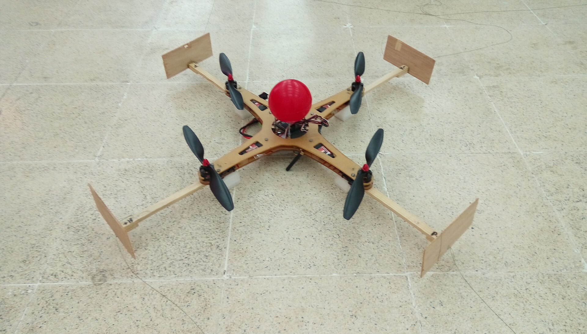 Student-built autonomous quadcopter on a workbench with its flight controller and wiring visible